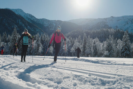 Eine Frau nimmt bei herrlichem Wetter am Achensee Langlaufcamp (Klassisch) in den verschneiten Karwendeltälern teil.