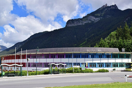 Das farbenfrohe Gebäude der Hauptschule Achensee in Maurach mit der Rotspitze im Hintergrund.