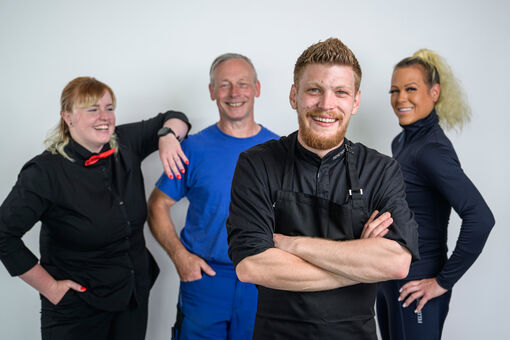 Group photo of a massage therapist, a riding instructor, a chef and a cable car staff member of the Achensee region.