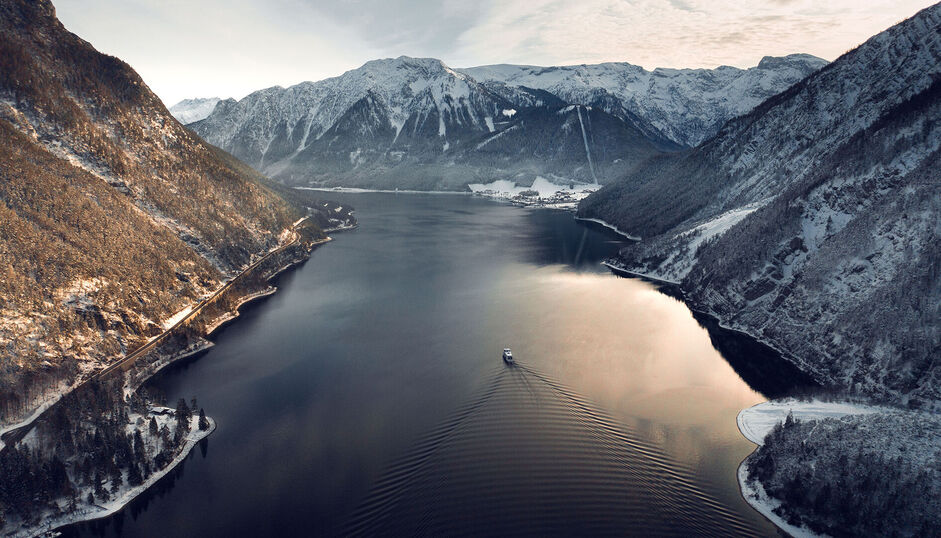 View of Lake Achensee and one of the Achensee ships in winter, the village of Pertisau and the snow-covered Karwendel mountains.