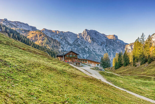 Die urige Bärenbadalm, umgeben von saftigen Wiesen und den majestätischen Gipfeln des Karwendelgebirges im Hintergrund.