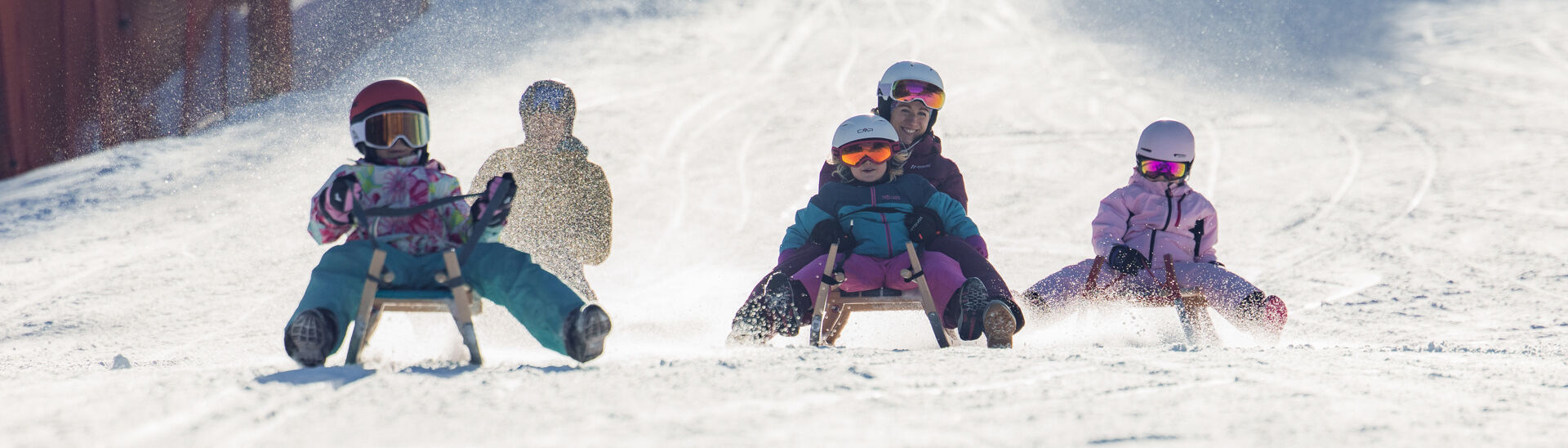 Rodelspaß in Achenkirch Bei herrlichem Wetter saust eine Familie die Rodelbahn in Achenkirch hinunter. Die Landschaft ist schneebedeckt.