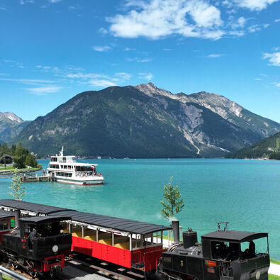 Bahn und Schiff am Achensee Die Luftaufnahme zeigt ein Schiff der Achenseeschifffahrt sowie die Achenseebahn an der Anlegestelle Seespitz im Sommer.