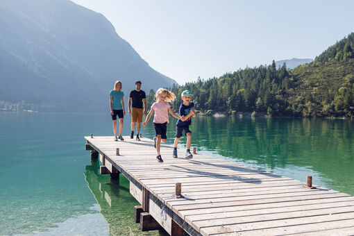 A family taking a break on a wooden pier during their hike on the Gaisalmsteig, enjoying the beautiful surroundings.
