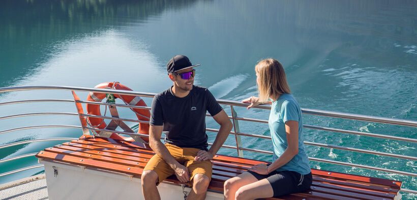 Ein Pärchen begibt sich auf einen Ausflug mit der Achenseeschifffahrt, um gemeinsam das Wasser und die malerische Landschaft in vollen Zügen zu genießen.