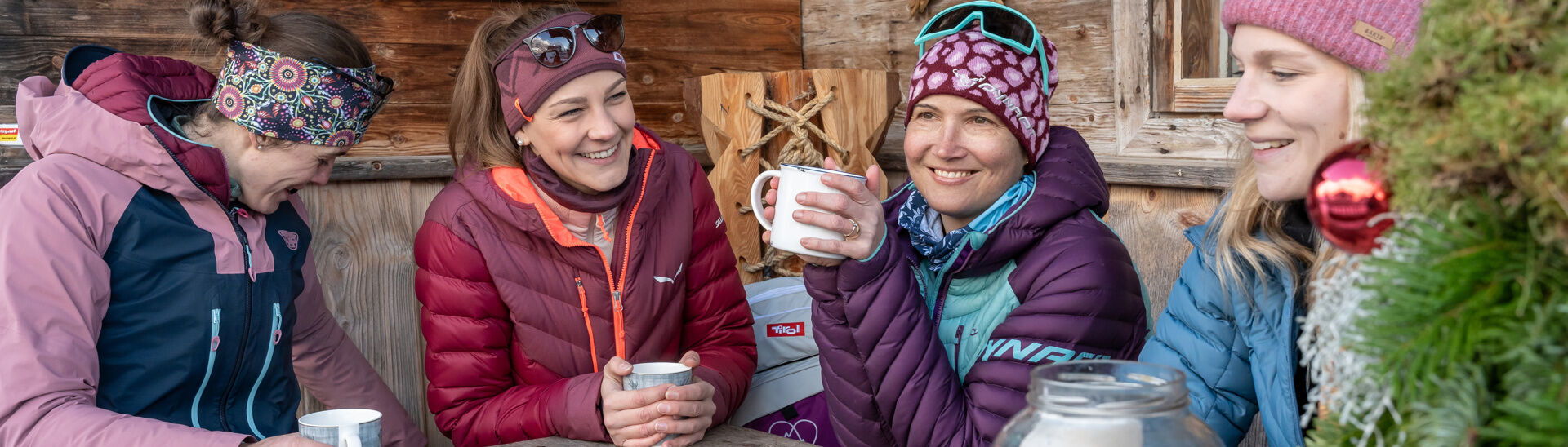 A group of friends enjoy tea and a snack on the terrace of a mountain hut.