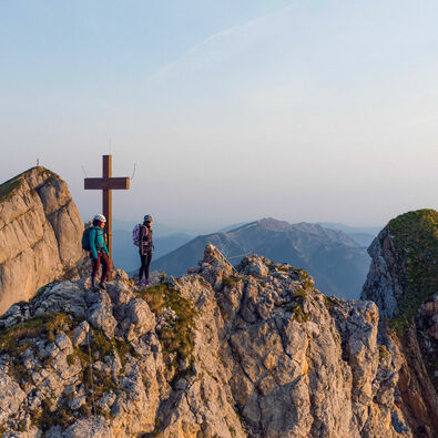 Zwei bergsportbegeisterte Frauen genießen die Morgenstimmung am Klettersteig Rosskopf im Rofangebirge.