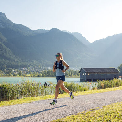 A woman jogs along the Seespitz in fine weather, while the boathouse can be seen in the background.