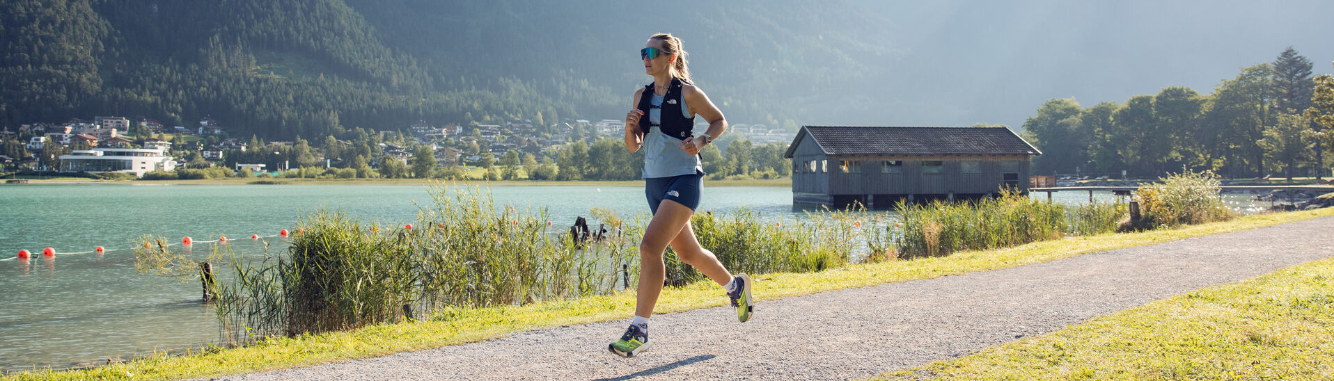 A woman jogs along the Seespitz in fine weather, while the boathouse can be seen in the background.