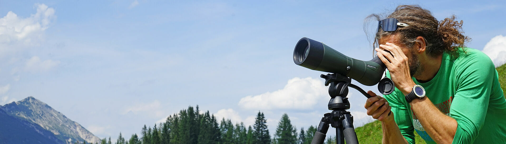Steinadlerwanderung im Naturpark Karwendel Ein Mann schaut durch sein Teleskop einer Steinadlerwanderung im Naturpark Karwendel zu.