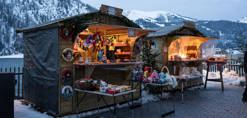 The Christmas market on the Scholastika pier in Achenkirch am Achensee attracts visitors with brightly lit market stalls selling artisan wares.