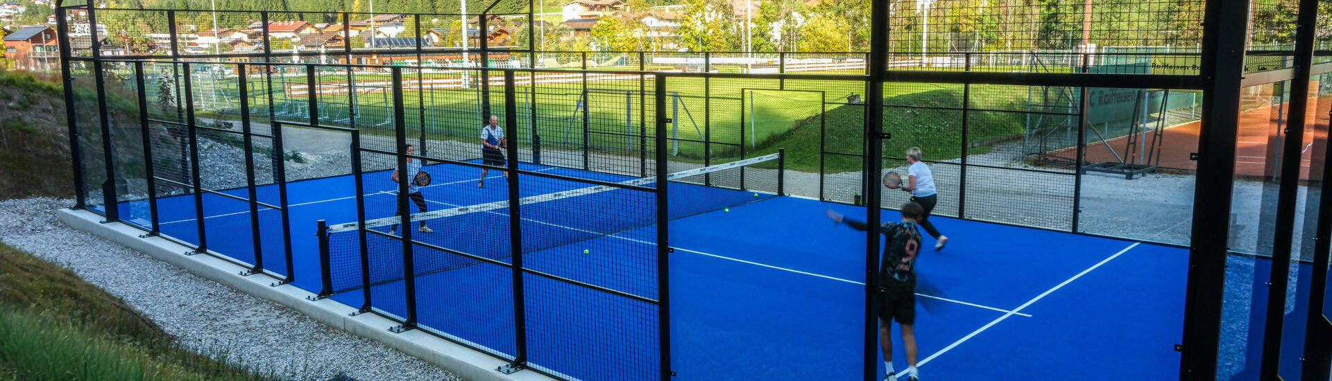 Vier Spieler liefern sich ein spannendes Match auf dem Padelplatz in Achenkirch am Achensee.