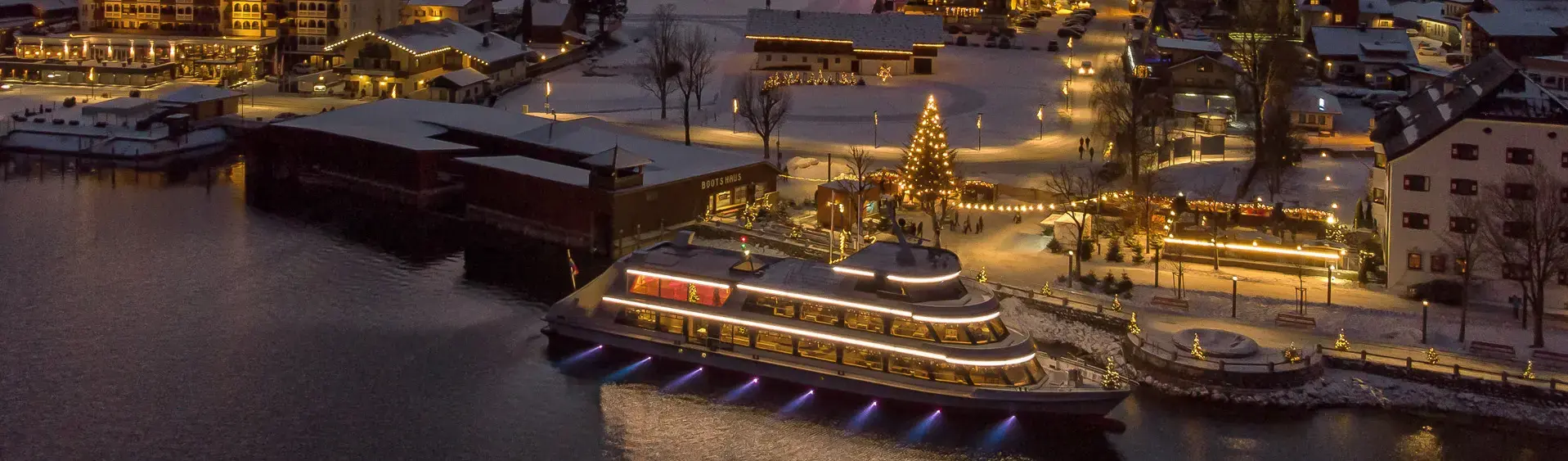 Die mit Schnee bedeckte Ortschaft Pertisau am Achensee wird in der Adventzeit wunderschön beleuchtet bei Nacht.
