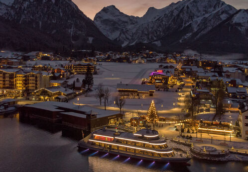 Weihnachtslinie der Achenseeschifffahrt Die mit Schnee bedeckte Ortschaft Pertisau am Achensee wird in der Adventzeit wunderschön beleuchtet bei Nacht.