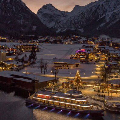 Die mit Schnee bedeckte Ortschaft Pertisau am Achensee wird in der Adventzeit wunderschön beleuchtet bei Nacht.