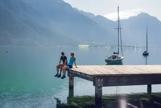 Holzsteg in Pertisau am Achensee Mit dem Partner die Umgebung rund um die Seeuferpromenade und den dazugehörigen Holzsteg in Pertisau erkunden und genießen. Im Hintergrund das Ebner Joch und einige Segelboote.