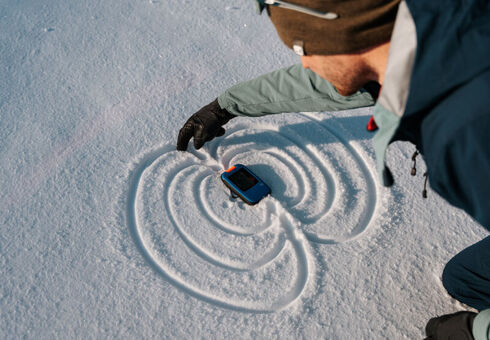 Ein Skitourengeher hält sein lebensrettendes Lawinenverschüttetensuchgerät (LVS) in der Hand.