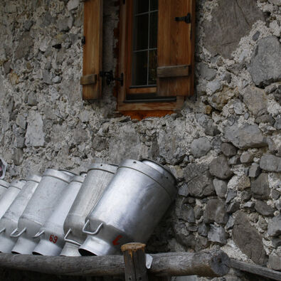 Große Milchkannen wurden hier an die Steinmauern der Alm im Falzthurntal gelehnt.