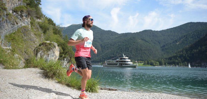 A participant on the trail route of the Achensee Run. The Achensee boat service can be seen in the background.