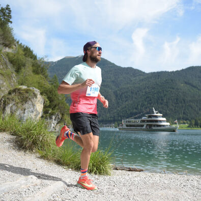 A participant on the trail route of the Achensee Run. The Achensee boat service can be seen in the background.