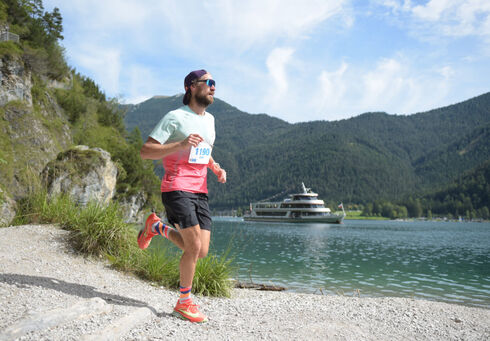 A participant on the trail route of the Achensee Run. The Achensee boat service can be seen in the background.