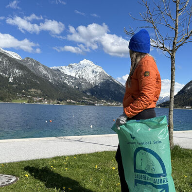 Eine junge Frau sammelt Müll an der Seeuferpromenade in Pertisau.