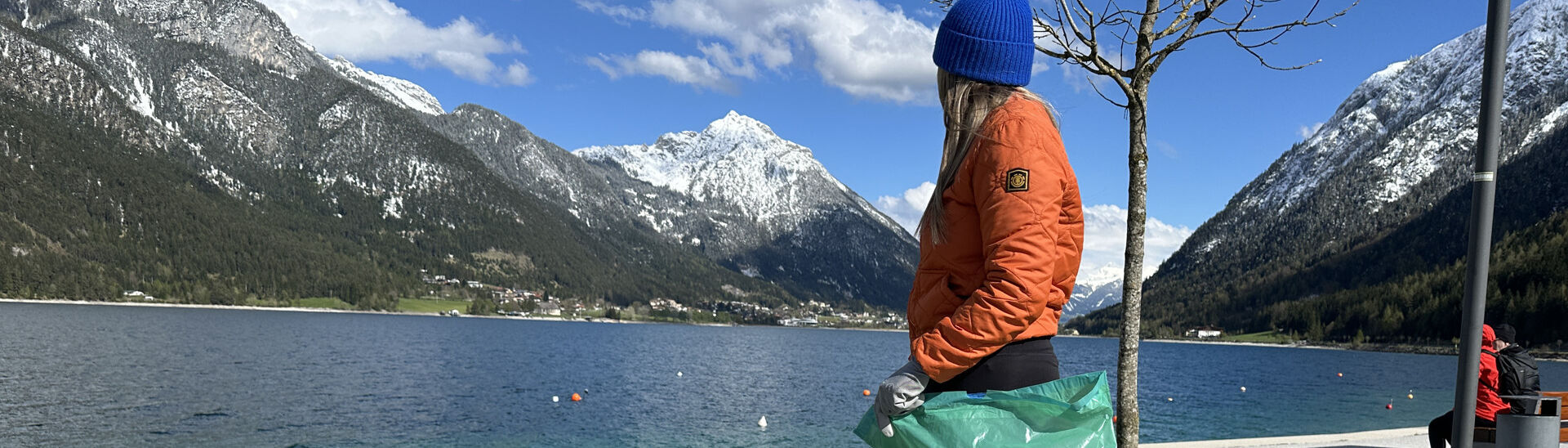 Eine junge Frau sammelt Müll an der Seeuferpromenade in Pertisau.