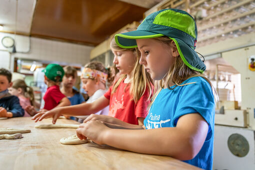 The day starts early in the morning at the Adler bakery in Achenkirch. Children learn how to make bread rolls.