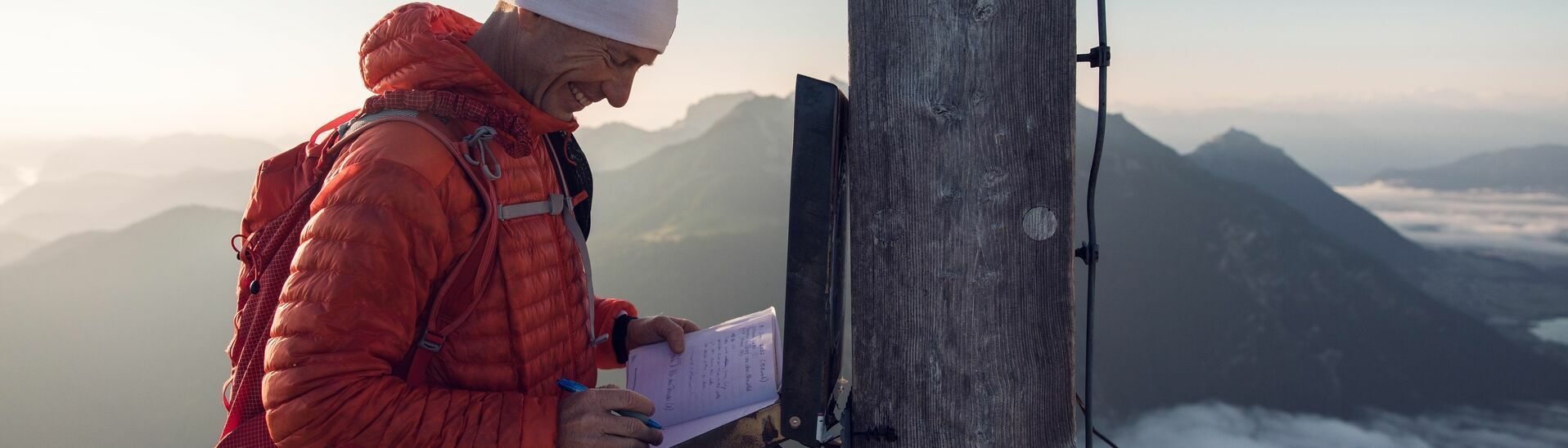 Gipfelbucheintrag auf der Seekarspitze im Karwendelgebirge Ein Bergläufer der sich im Gipfelbuch der Seekarspitze im Karwendelgebirge einträgt bei einer schönen Aussicht auf die nebeligen Täler.