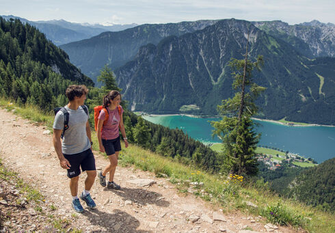 Ein Pärchen wandert entlang eines Wanderweges im Rofangebirge und genießt die tolle Wiese rundherum.