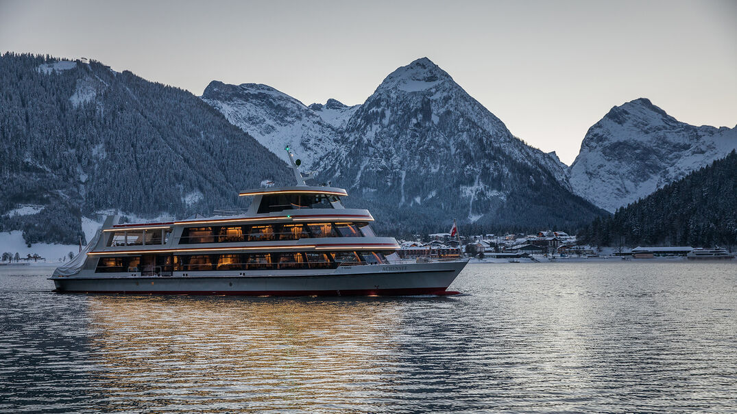 Achenseeschifffahrt in the evening The MS Achensee cruising over Lake Achensee on a winter evening. In the background of this photo is the village of Pertisau and the Karwendel mountains.