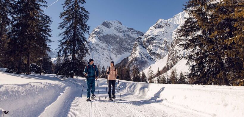 Ein Paar unternimmt bei herrlichem Wetter eine Schneeschuhwanderung im Falzthurntal im Naturpark Karwendel.