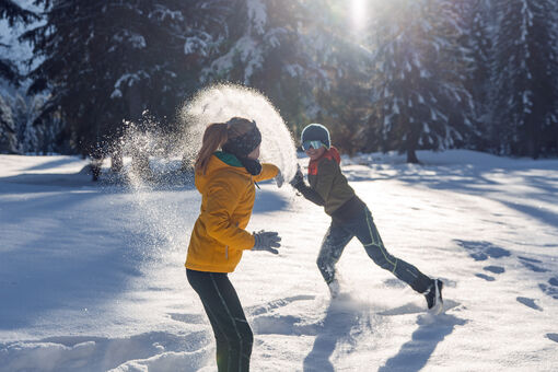Zwei Geschwister toben im frisch gefallenen Neuschnee und genießen bei strahlendem Wetter die gemeinsame Zeit in den Karwendeltälern.