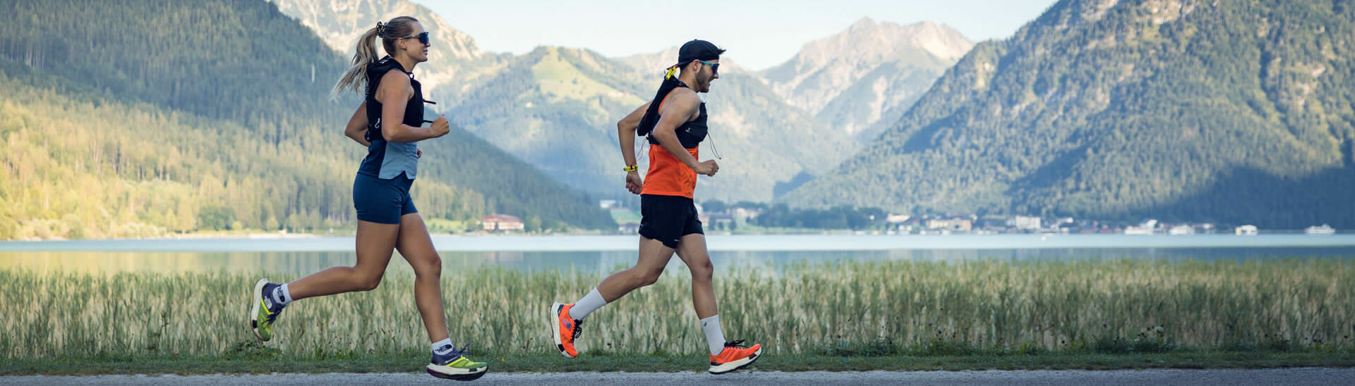Zwei Läufer joggen bei schönem Wetter am Seespitz entlang, im Hintergrund ist der Achensee zu sehen.