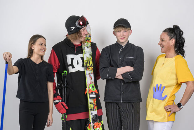 This photo captures a hotel housekeeper, a skier, an apprentice chef and a care worker holding the Achensee DahoamCard in front of a white screen.