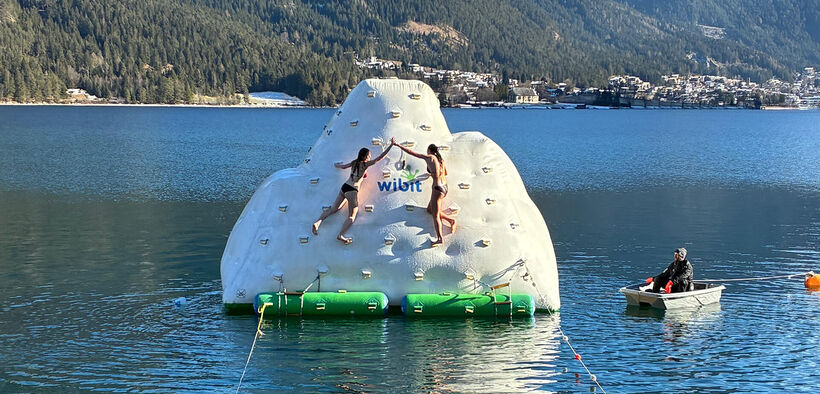 During the New Year's Eve swim at Lake Achensee, two participants climb an air-filled iceberg in glorious weather and ring the bell.
