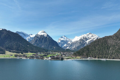 Pertisau on Lake Achensee in spring with snow-covered mountain peaks.