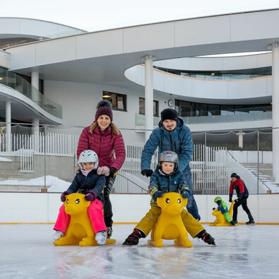 Eine Familie genießt den Wintertag auf dem Eislaufplatz des Atoll Achensee in Maurach.