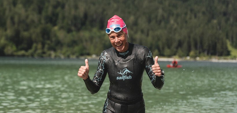 Eine Teilnehmerin beim Langstreckenschwimmen am Achensee lacht fröhlich in die Kamera.