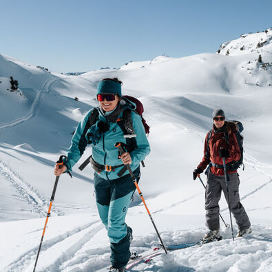 Participants of the Achensee ski tour camp enjoy skinning uphill in the Rofan mountains on a sunny day.