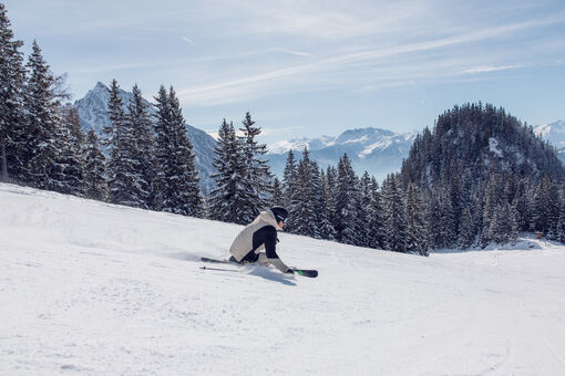 A skier enjoys the sunny winter day on the perfectly groomed slopes of the Rofan mountains overlooking the Nature Park Karwendel.
