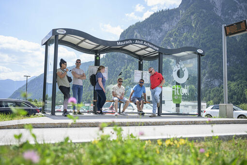 A group of people waiting for the next bus at the bus stop of the Atoll Achensee.