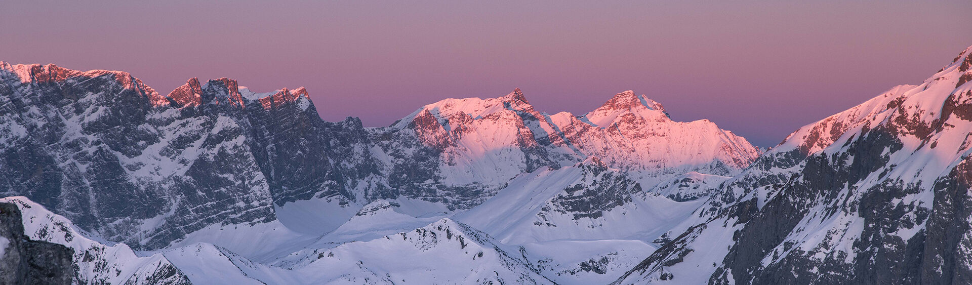 Blick auf den Naturpark Karwendel Der Blick auf den winterlichen Naturpark Karwendel bei Sonnenaufgang ist magisch. Die Gipfel und der Himmel färben sich violett und rosarot.