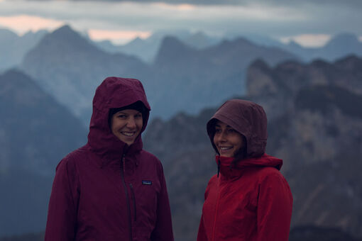 Two young women hiking well equipped in the Rofan mountains in cloudy weather.