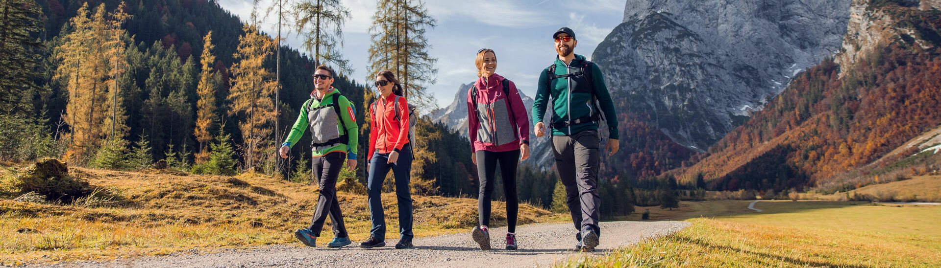Eine Gruppe von Freunden nutzt das schöne Wetter für eine Herbstwanderung durch das bunt gefärbte Falzthurntal im Naturpark Karwendel.