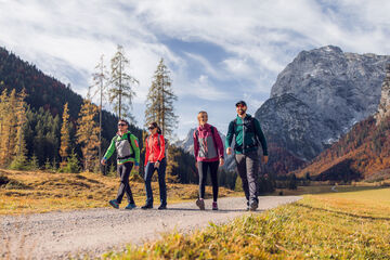 Eine Gruppe von Freunden nutzt das schöne Wetter für eine Herbstwanderung durch das bunt gefärbte Falzthurntal im Naturpark Karwendel.