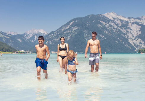 Badespaß mit der Familie in Maurach am Achensee Eine Familie genießt das schöne Wetter und badet im türkisblauen Achensee in Maurach.