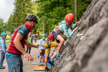 Eine Gruppe Jugendlicher die versuchen die 18 Meter hohe Kletterwand am Achenseehof mit Hilfe eines Guides zu erklimmen.
