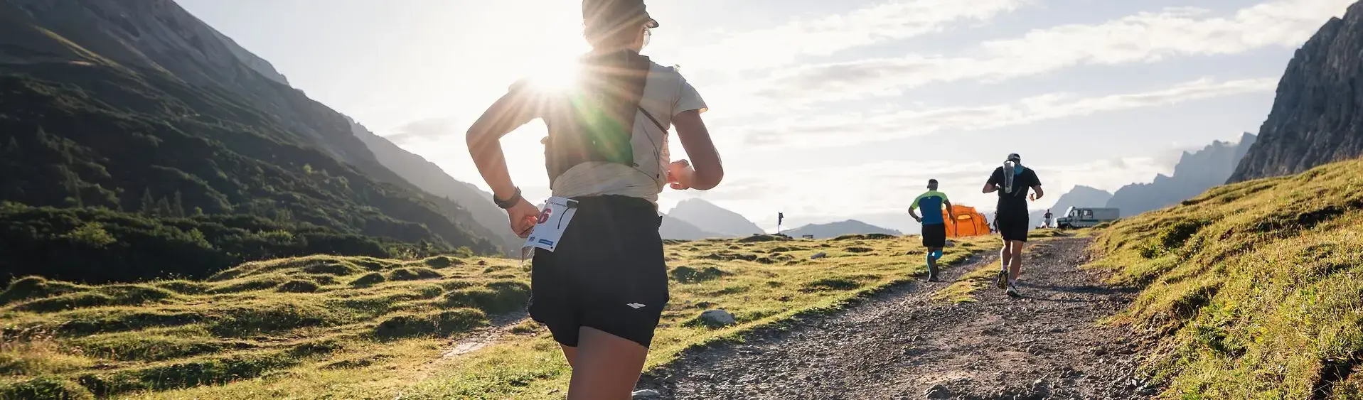 Eine Läuferin beim Karwendelmarsch 2026 Eine Läuferin beim Karwendelmarsch läuft im Licht des Sonnenaufgangs durch die alpine Landschaft im Naturpark.