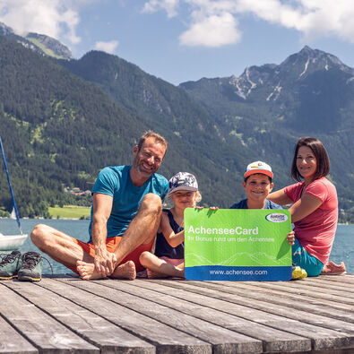 Eine Familie am Steg in Pertisau am Achensee mit der AchenseeCard in der Hand. 